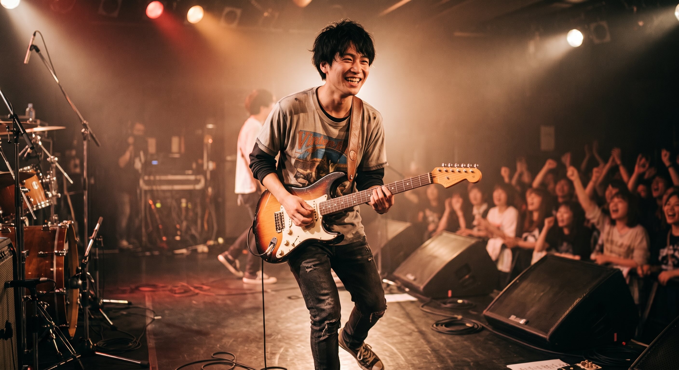 ライブハウスのステーで笑顔で活き活きとギターをかき鳴らしている男性