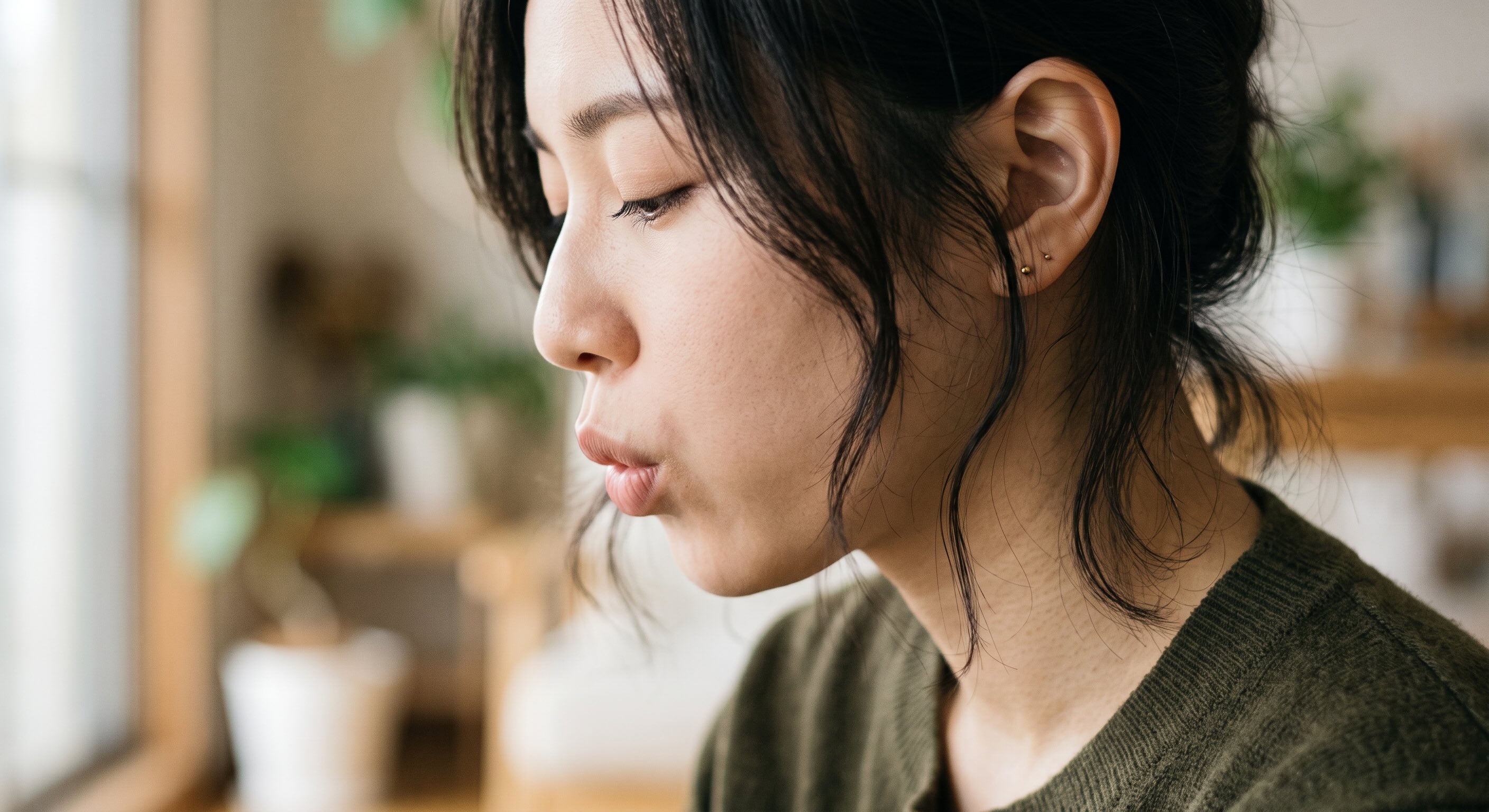 リラックスした口元で優しく息を吐き出している女性